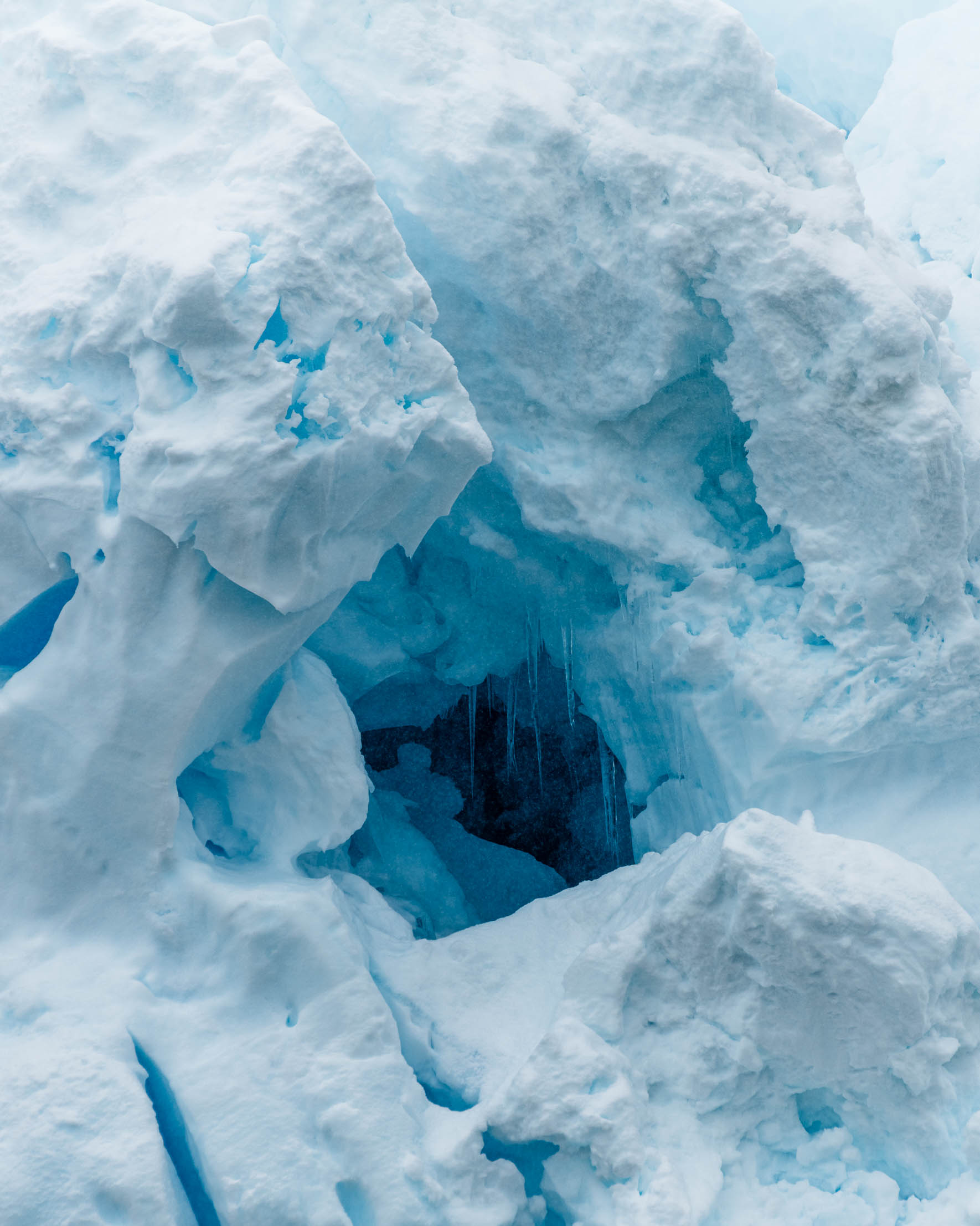 Blue glow and icicles inside a glacier hole