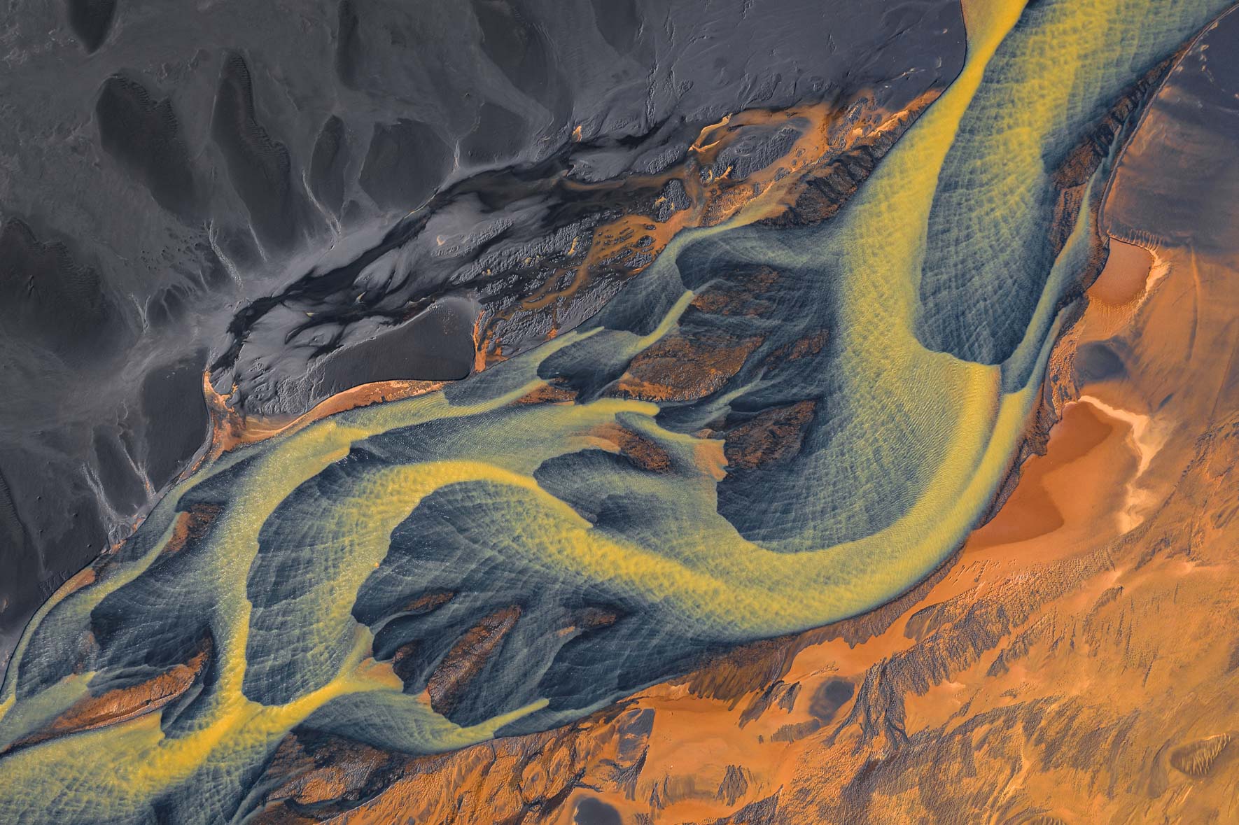 Abstract aerial photograph of colorful glacier river in Iceland with black sand
