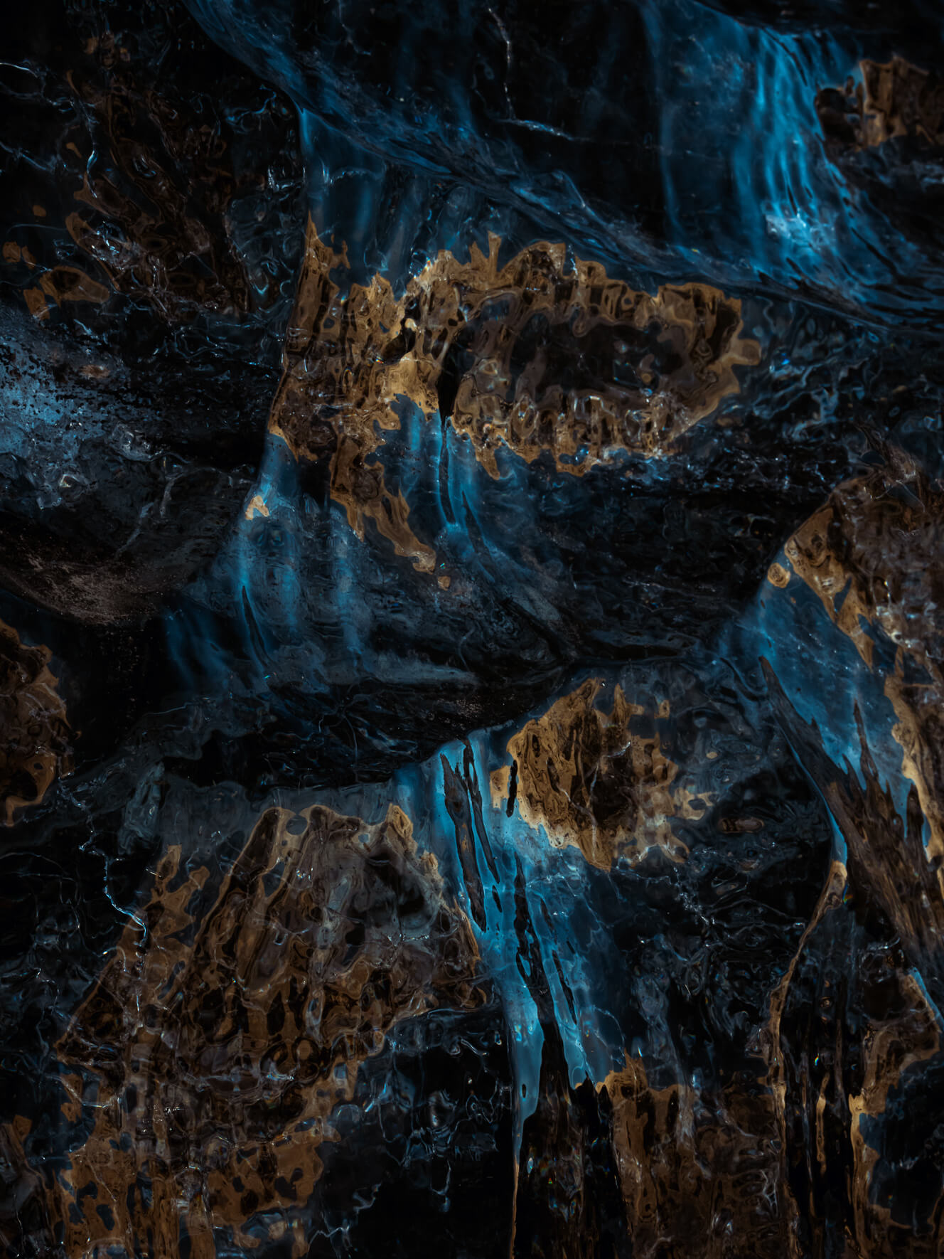 Sunlight reflecting on the dark glacial ice of the Vatnajökull glacier in Iceland, creating abstract patterns