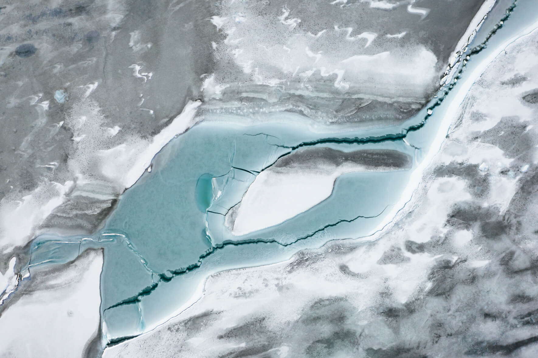 Aerial view of frozen glacier lagoon Jökulsárlón in Iceland with abstract patterns on the surface and cracks in the ice