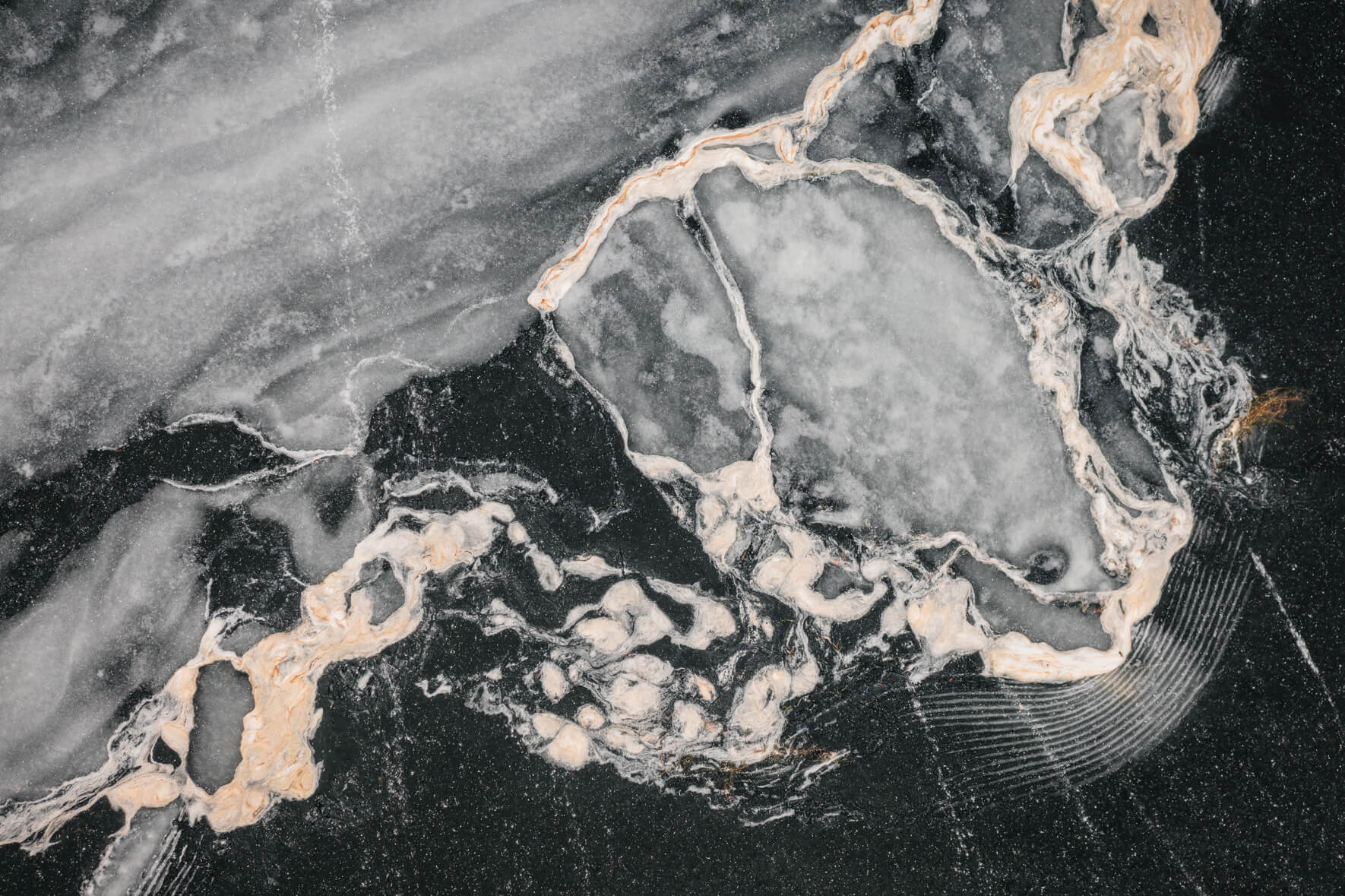 Aerial view of a frozen lake with abstract textures and patterns on the surface