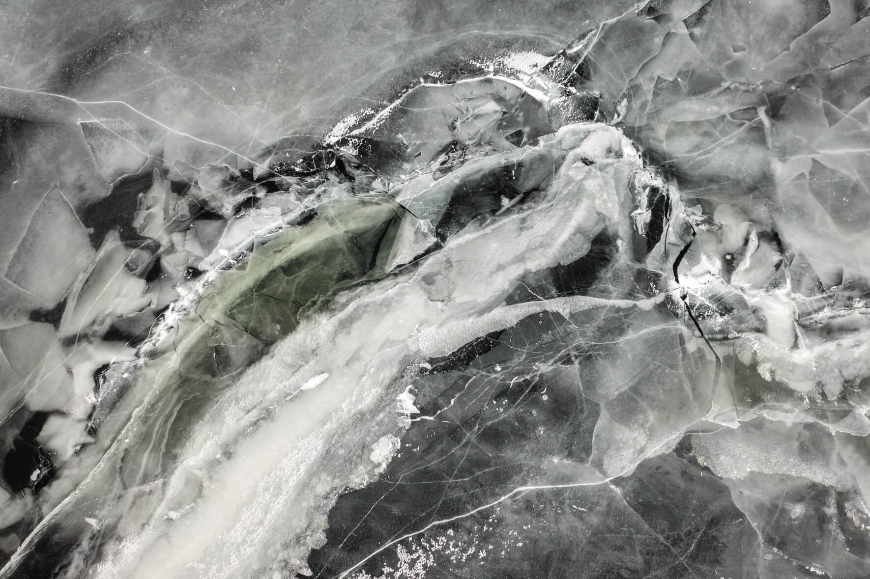 Aerial view of frozen lake Ã…raksfjorden with abstract textures and patterns and ice breaking apart