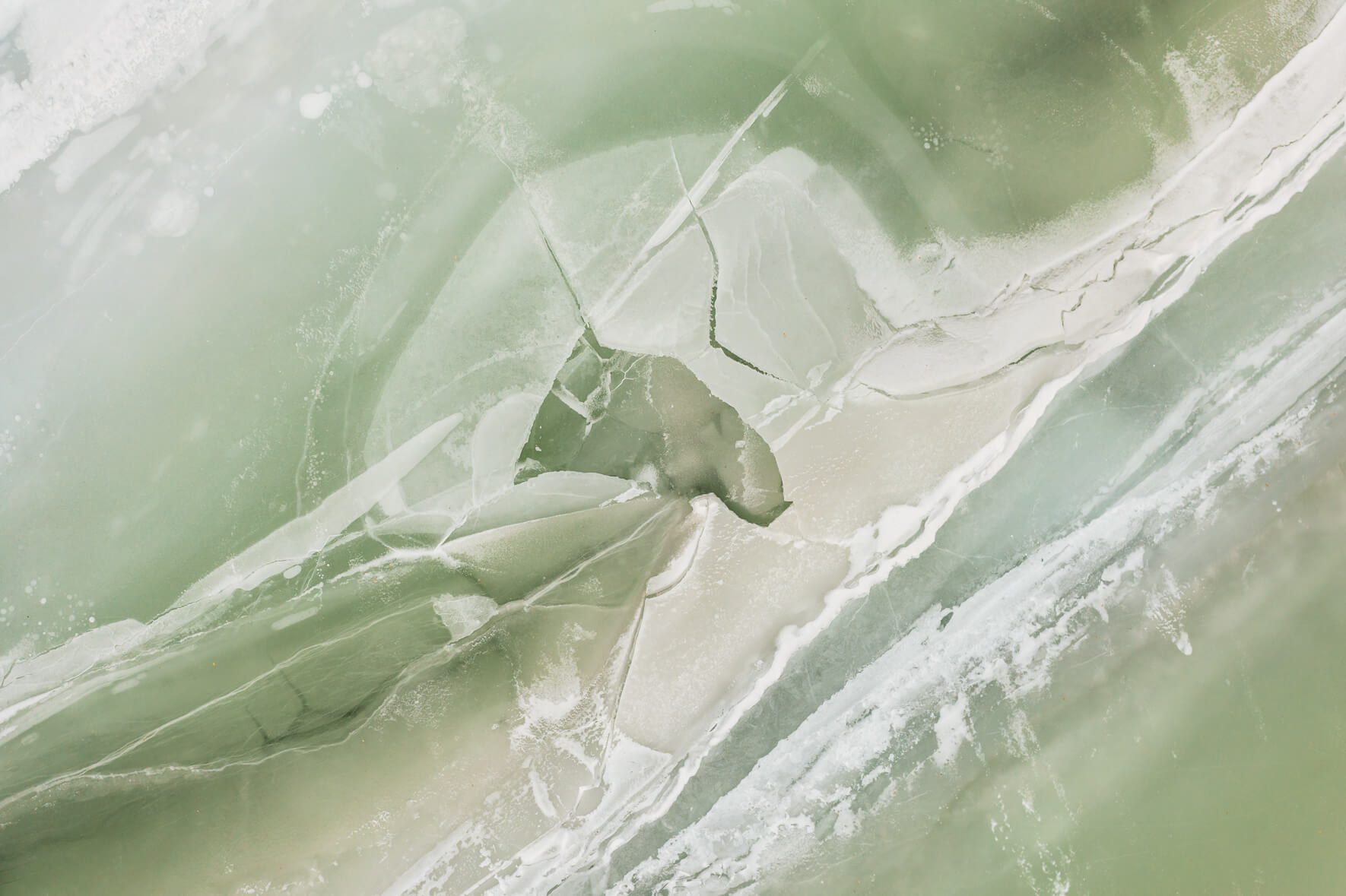 Aerial view of a frozen lake in Norway with cracks in the ice surface