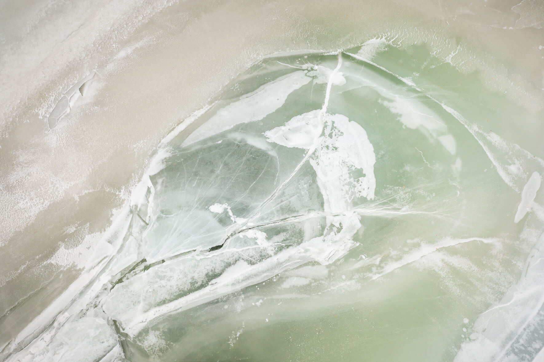 Ice of the frozen Ã…raksfjorden lake with a greenish tint due to algae