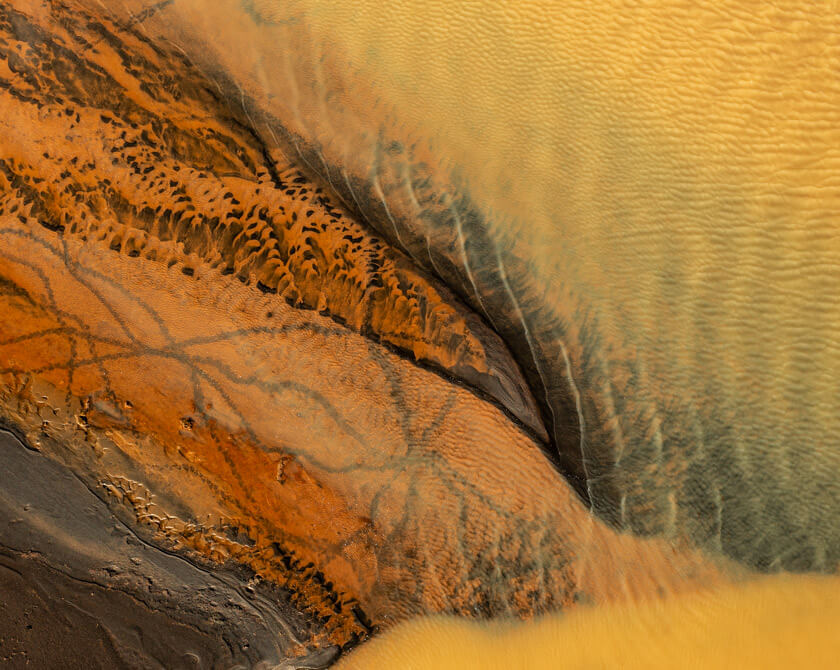 Drone perspective capturing the abstract patterns formed by sulphur deposits in an Icelandic river
