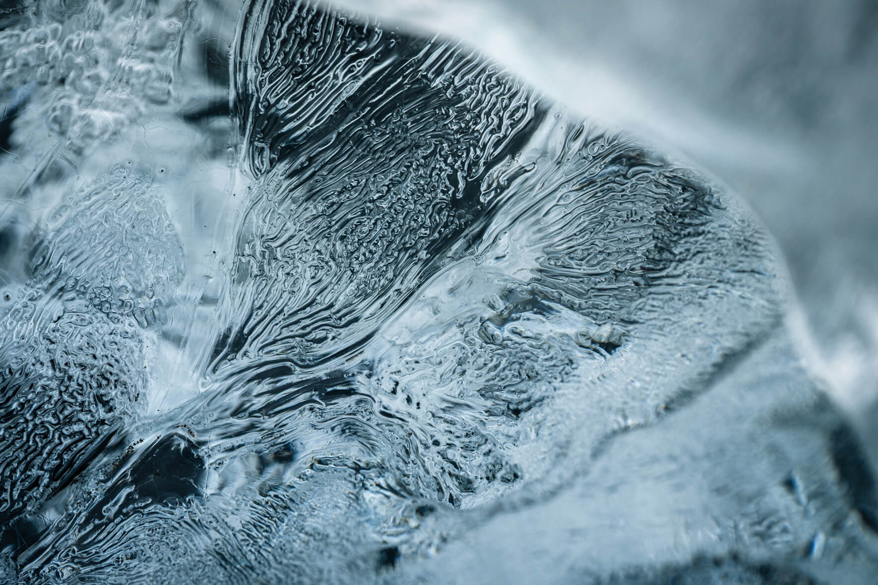 Close-up of blue iceberg fragment on black sand beach in Iceland with fine ice textures