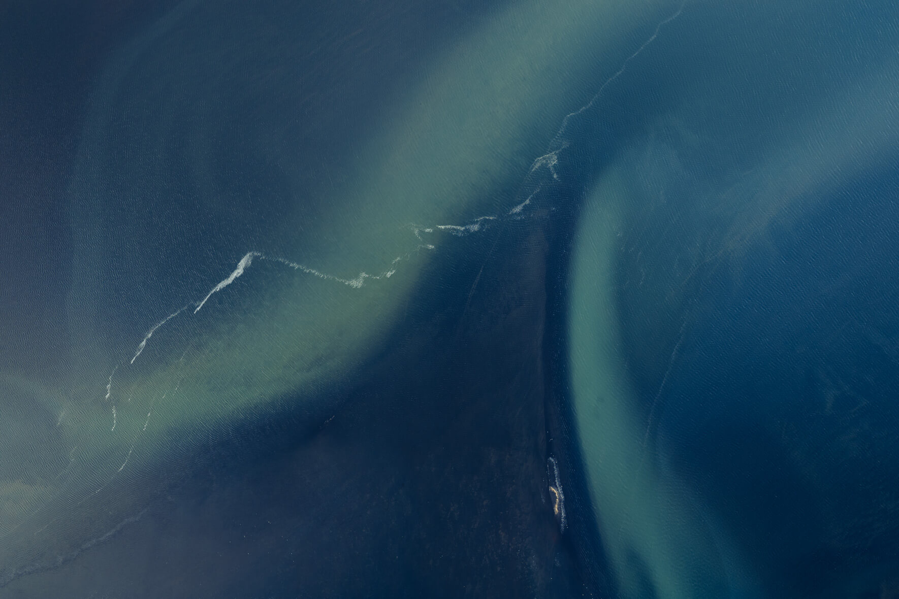 Aerial abstract of Icelandic lagoon showing swirling sediments in the water