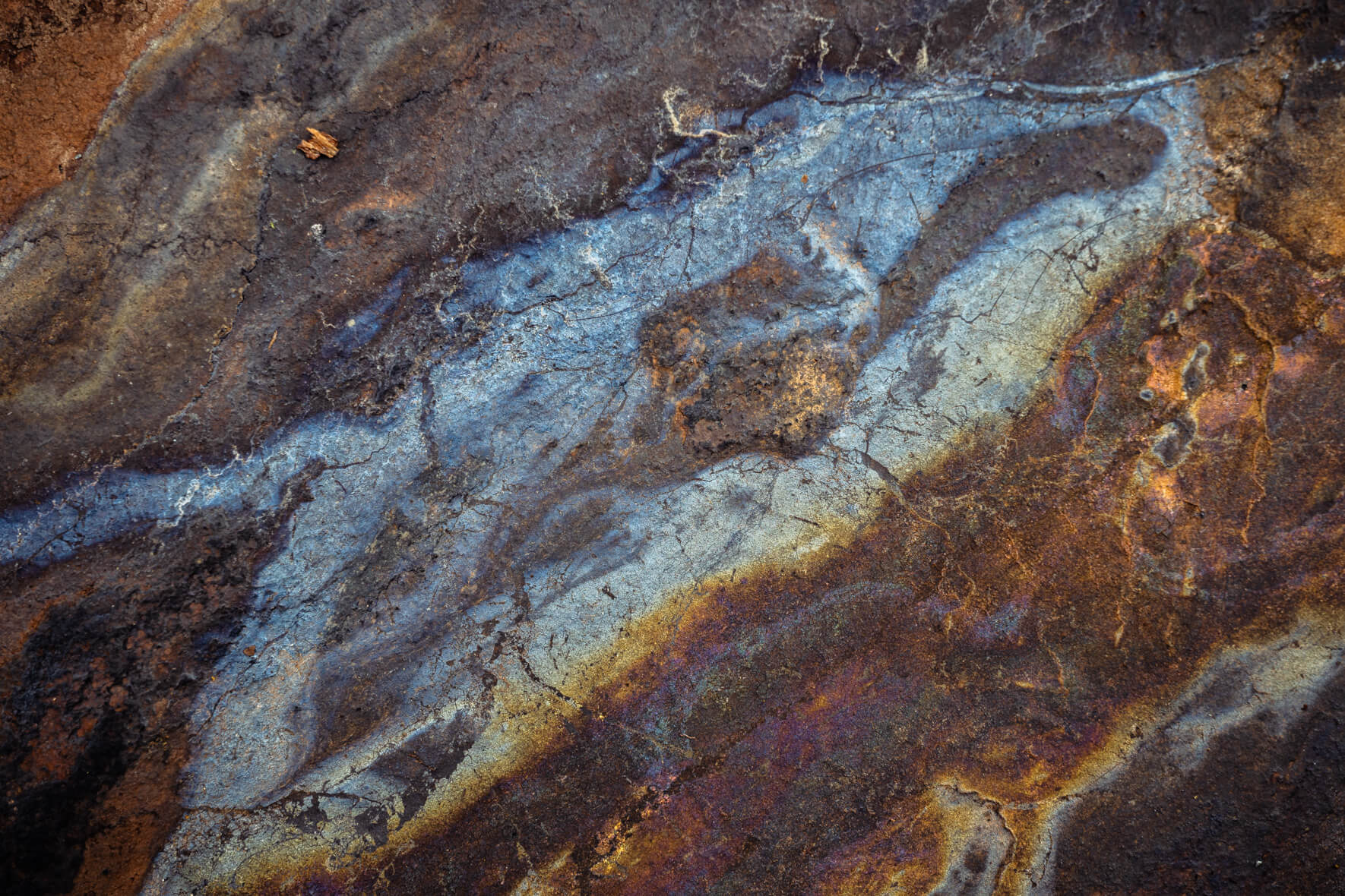 Oxidized rock with rich orange and blue mineral patterns