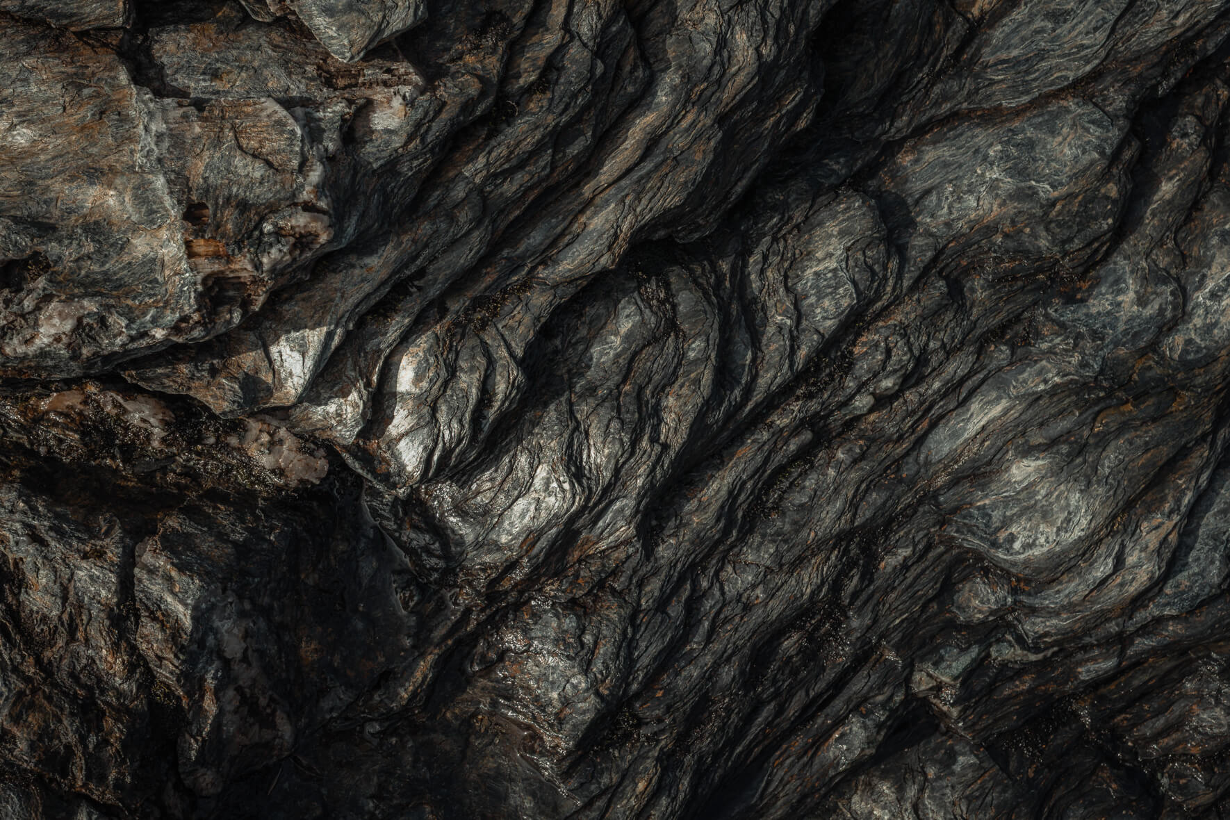 Folded rock surface with metallic reflections and natural erosion marks