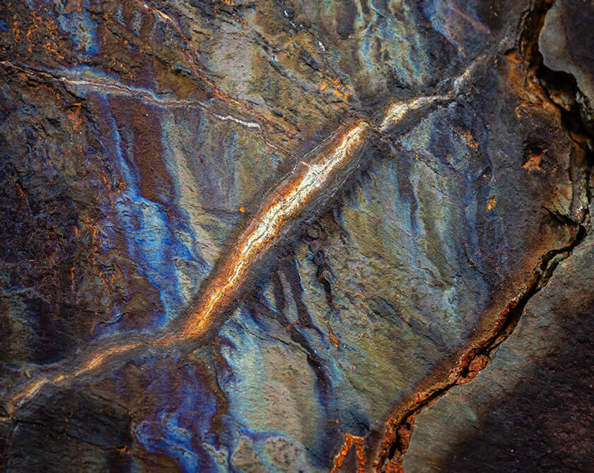 Oxidized rock with rich orange and blue mineral patterns and cracks