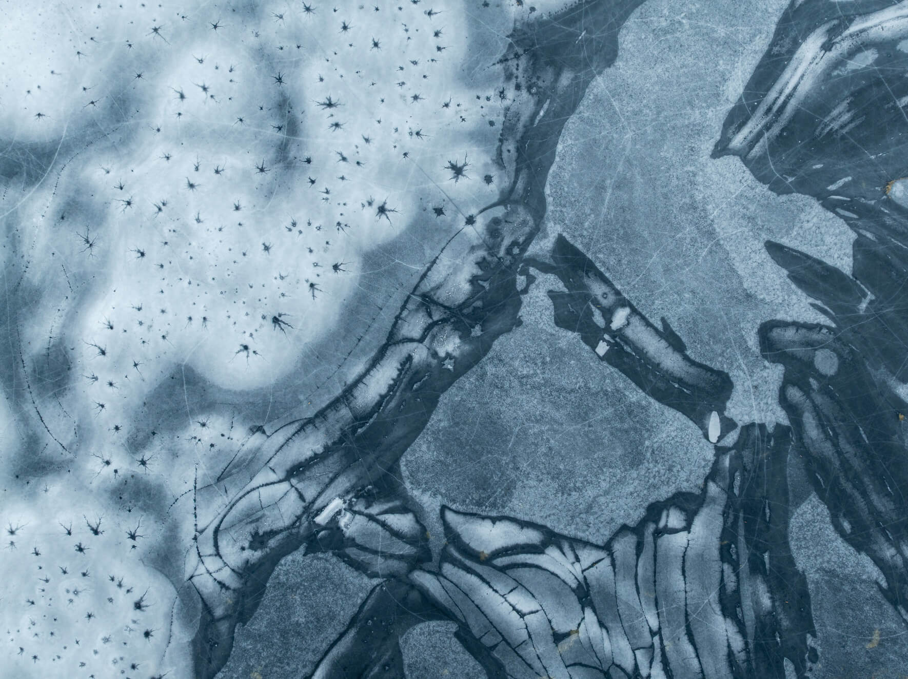 Aerial view of fractured frozen lake surface with geometric ice shapes