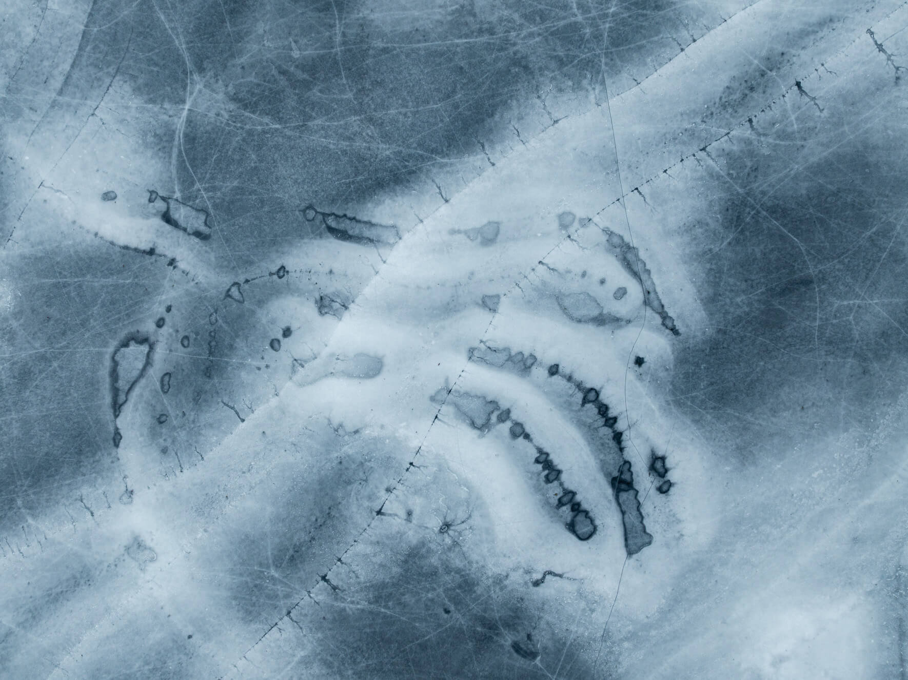 Aerial photograph of frozen lake surface with branching cracks in the ice