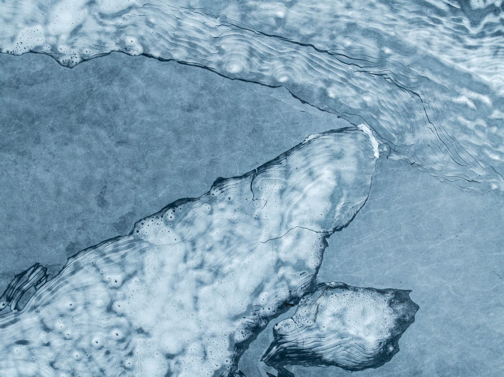Frozen lake patterns shaped by wind, frost, and melting layers in Norway