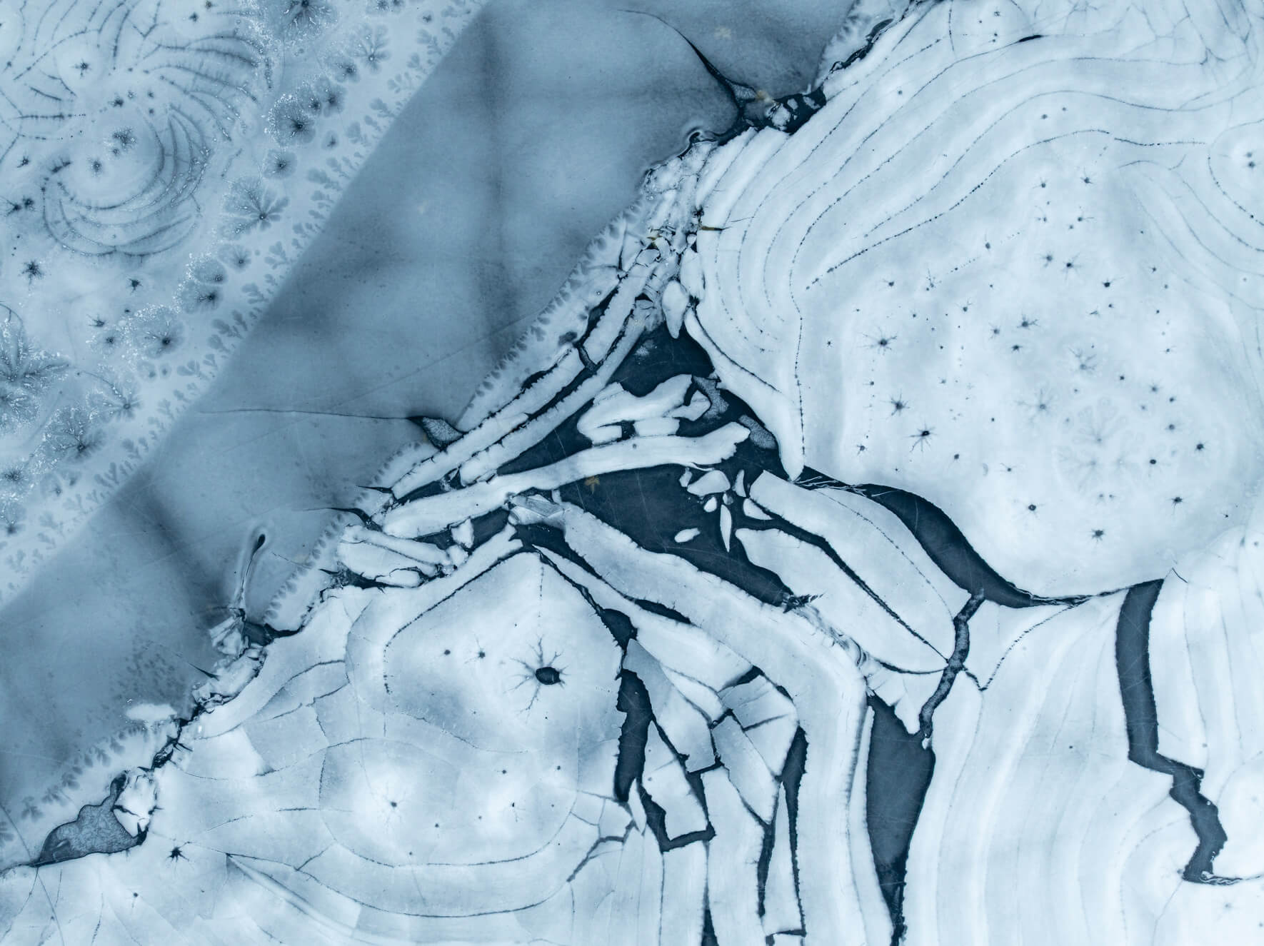 Aerial view of fractured frozen lake surface with geometric ice shapes in Norway