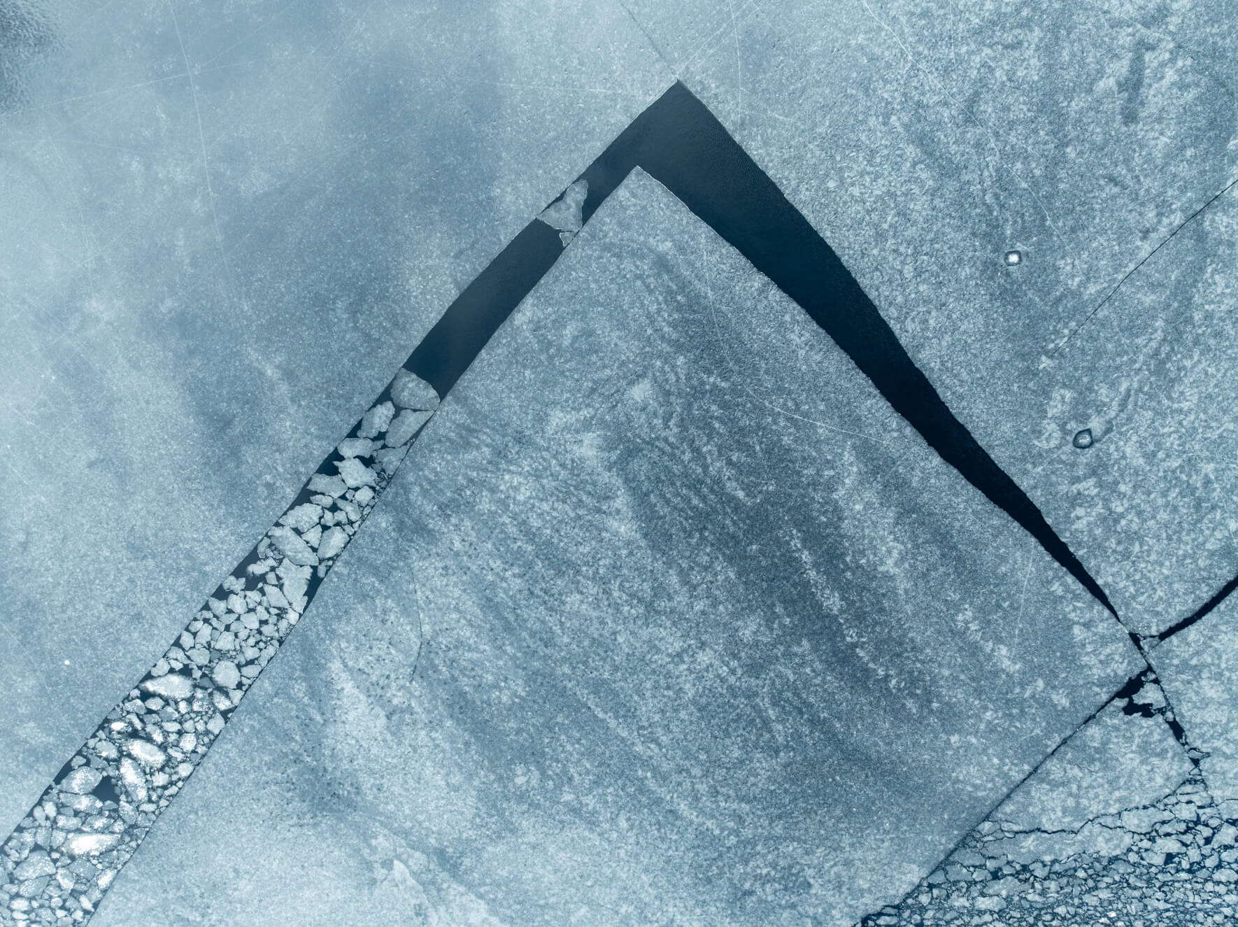 Aerial view of frozen lake with cracked ice and small ice floes floating in channel