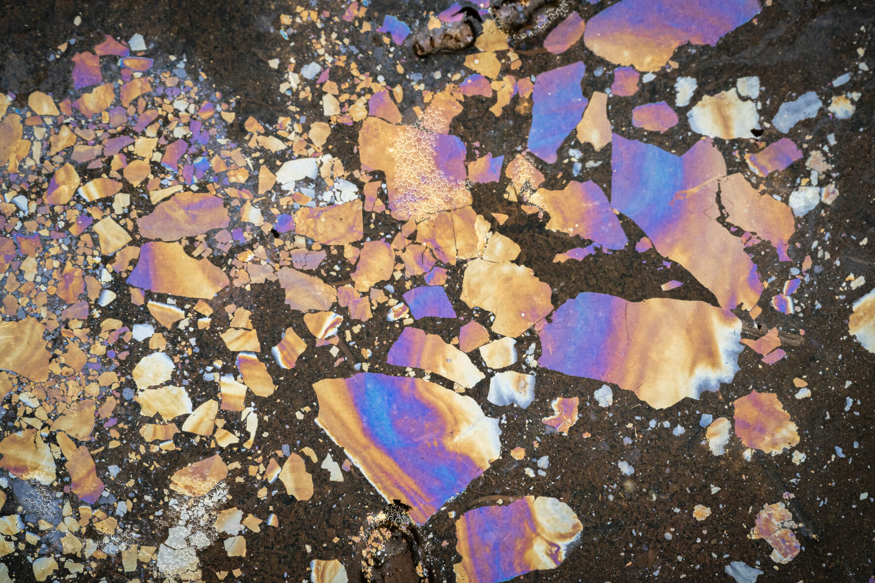 Colorful surface texture of oxidized water showing fine cracks and deep iridescent reflections