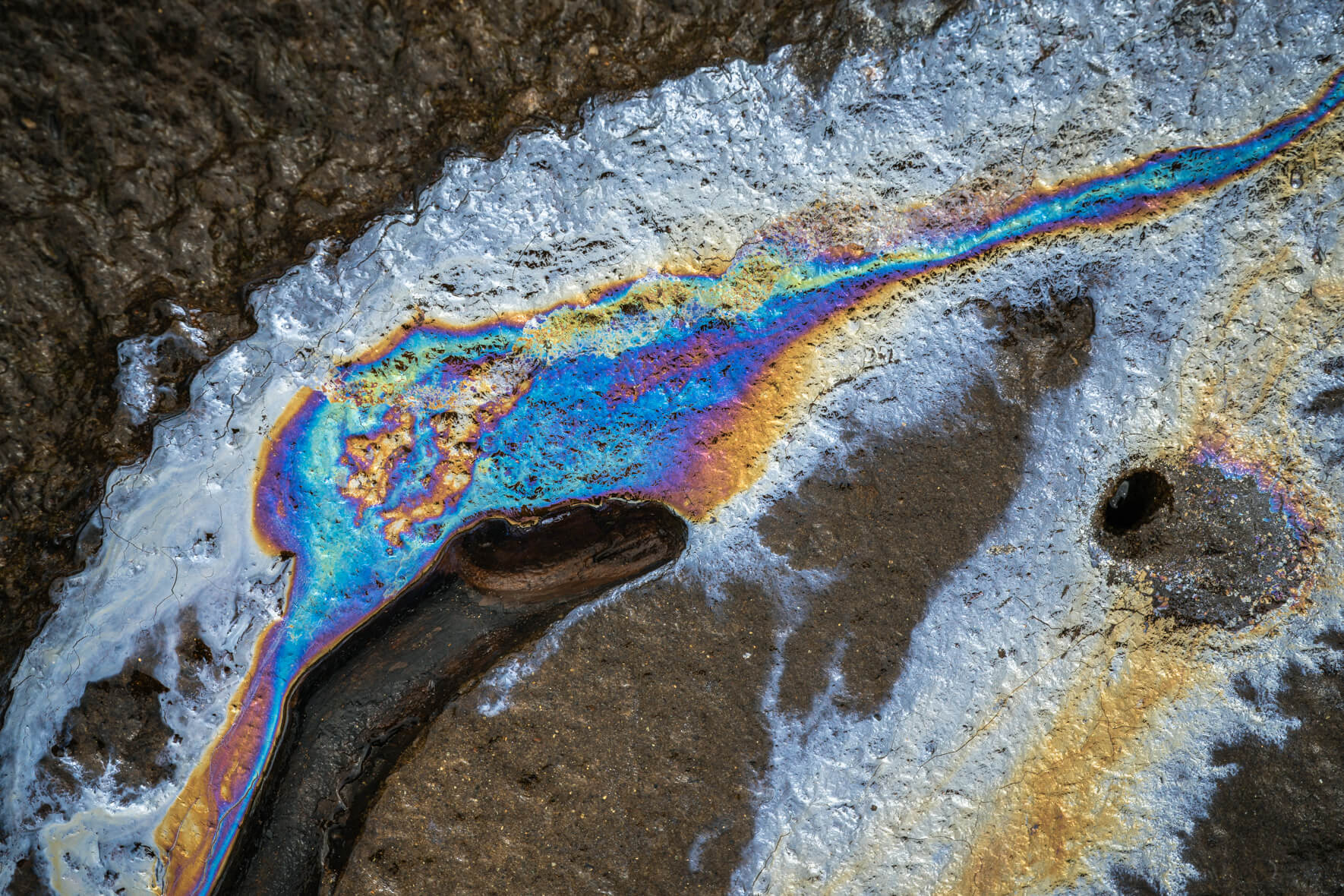 Fractured biofilm surface with glass-like textures and vivid iridescent highlights