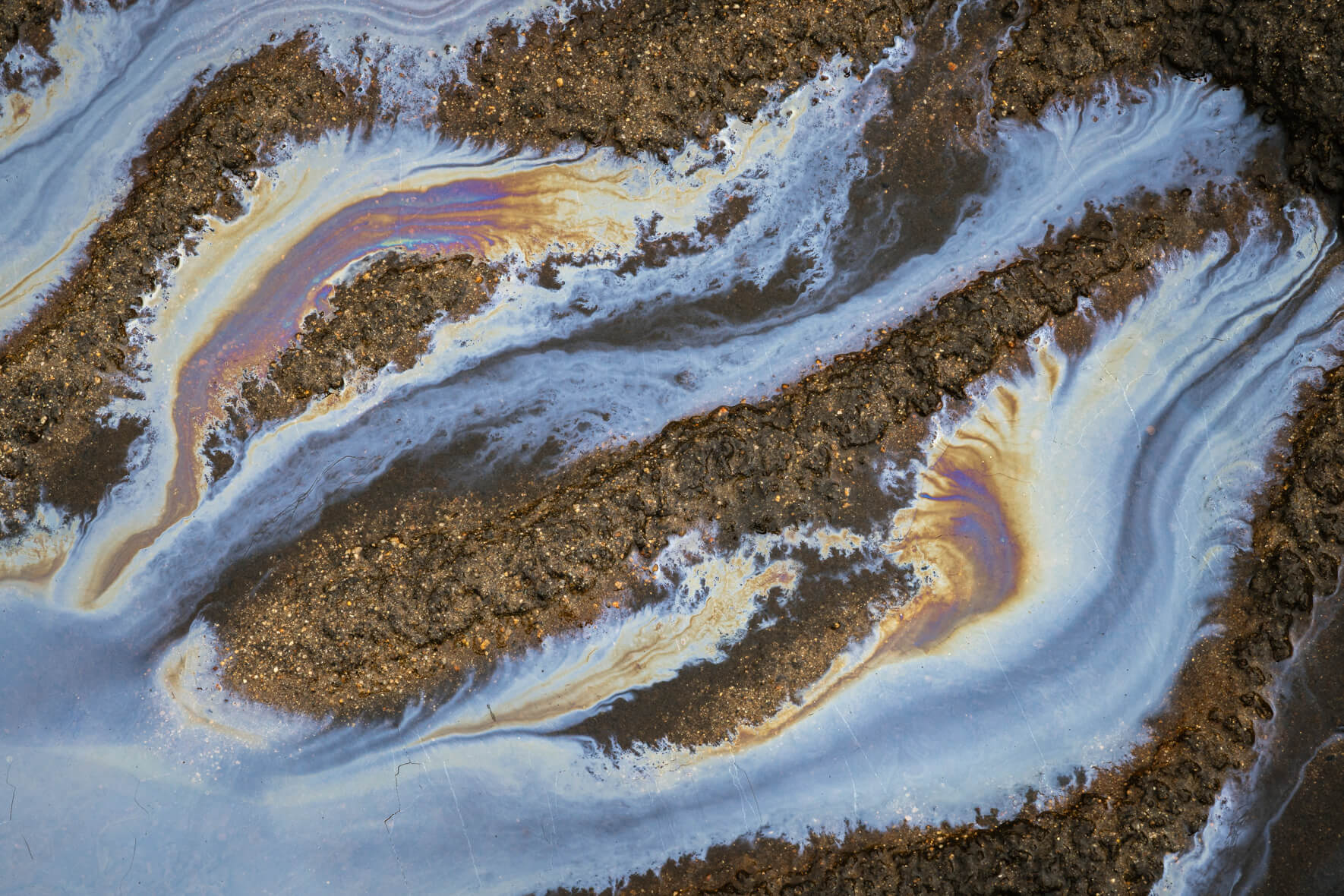 Oxidized water surface in Norway with vivid orange and deep blue bacterial textures
