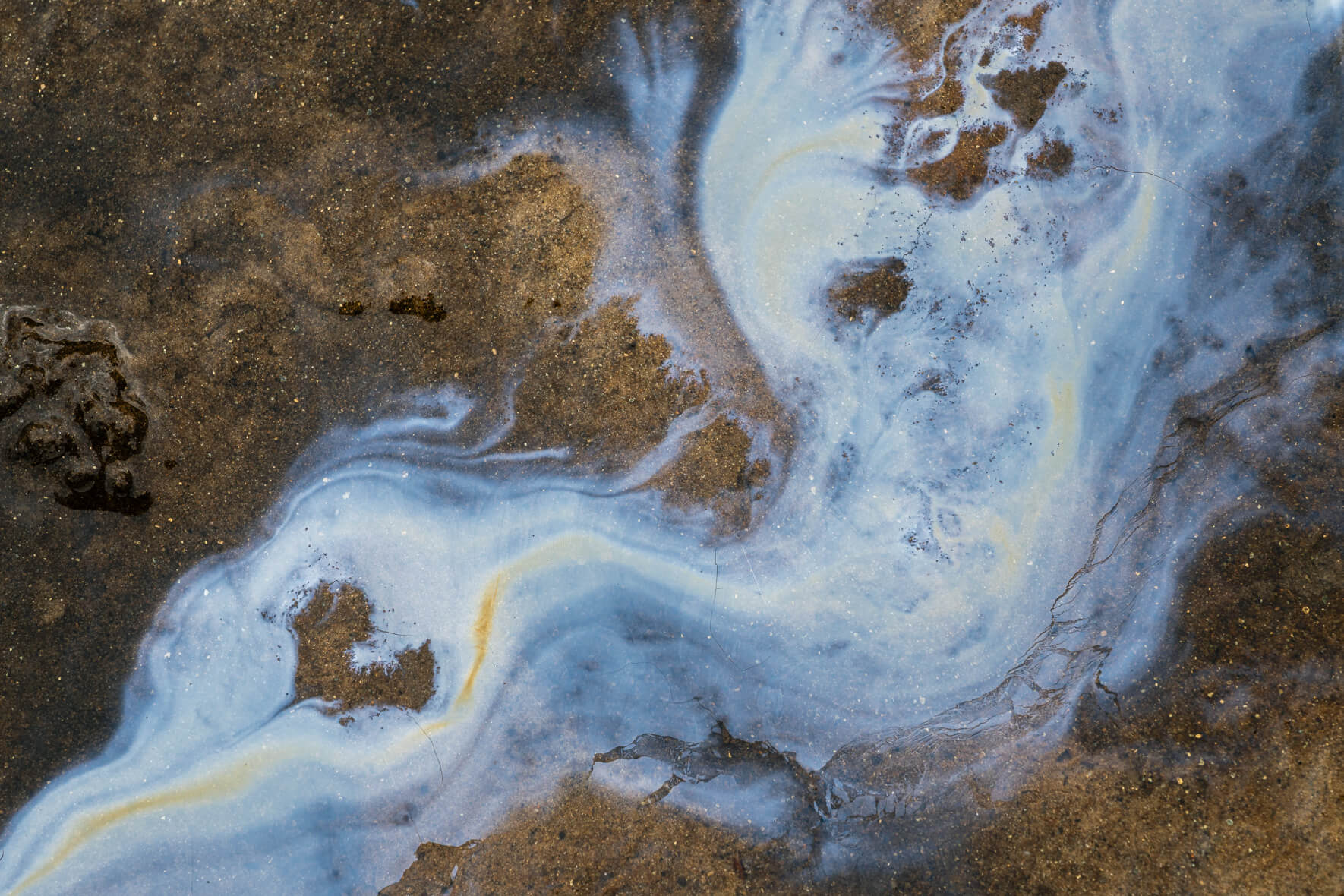 Metallic surface tones created by iron bacteria forming abstract circular structures