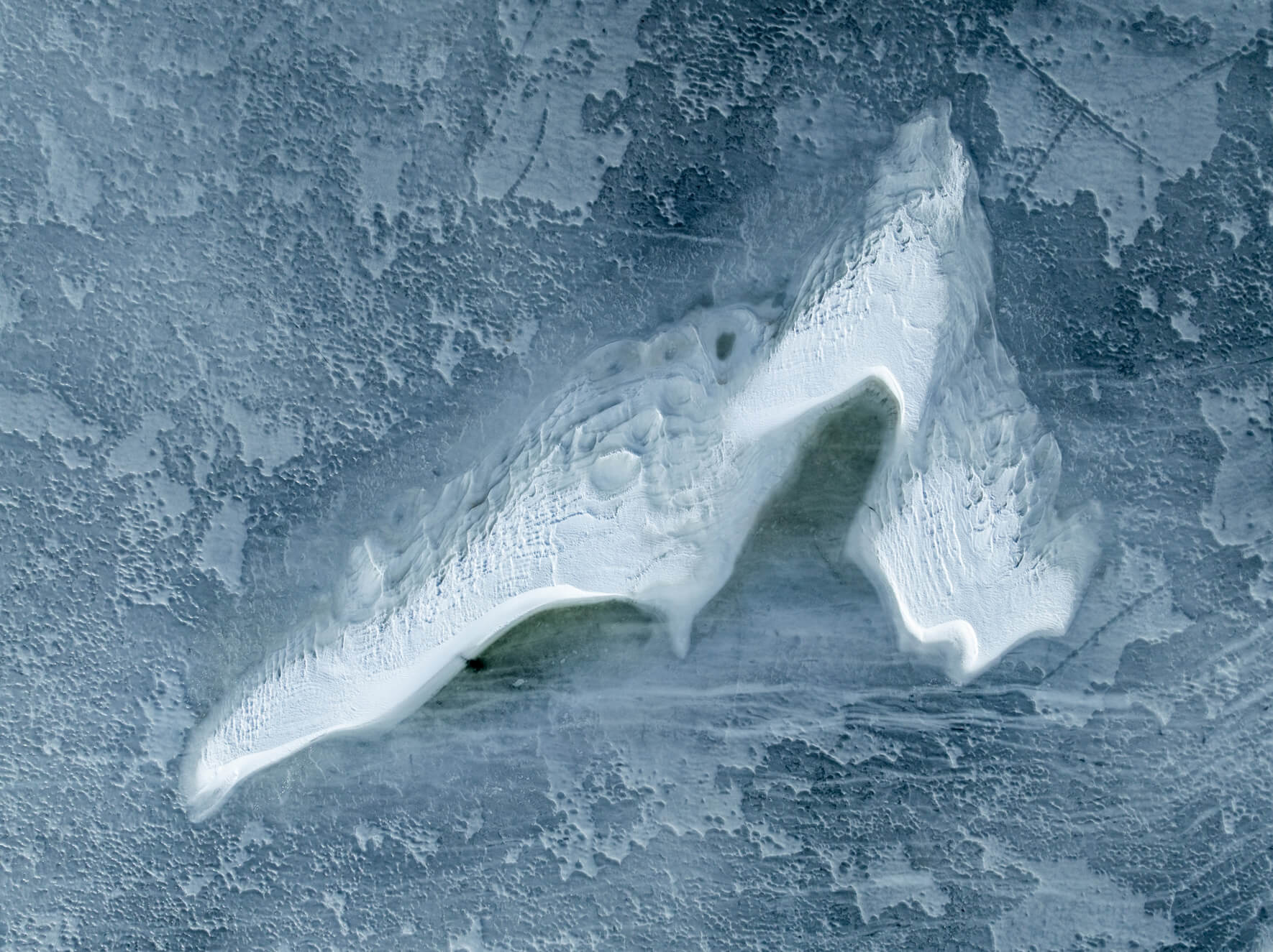 Aerial abstract of ice patterns blending frost, cracks, and drifting snow lines