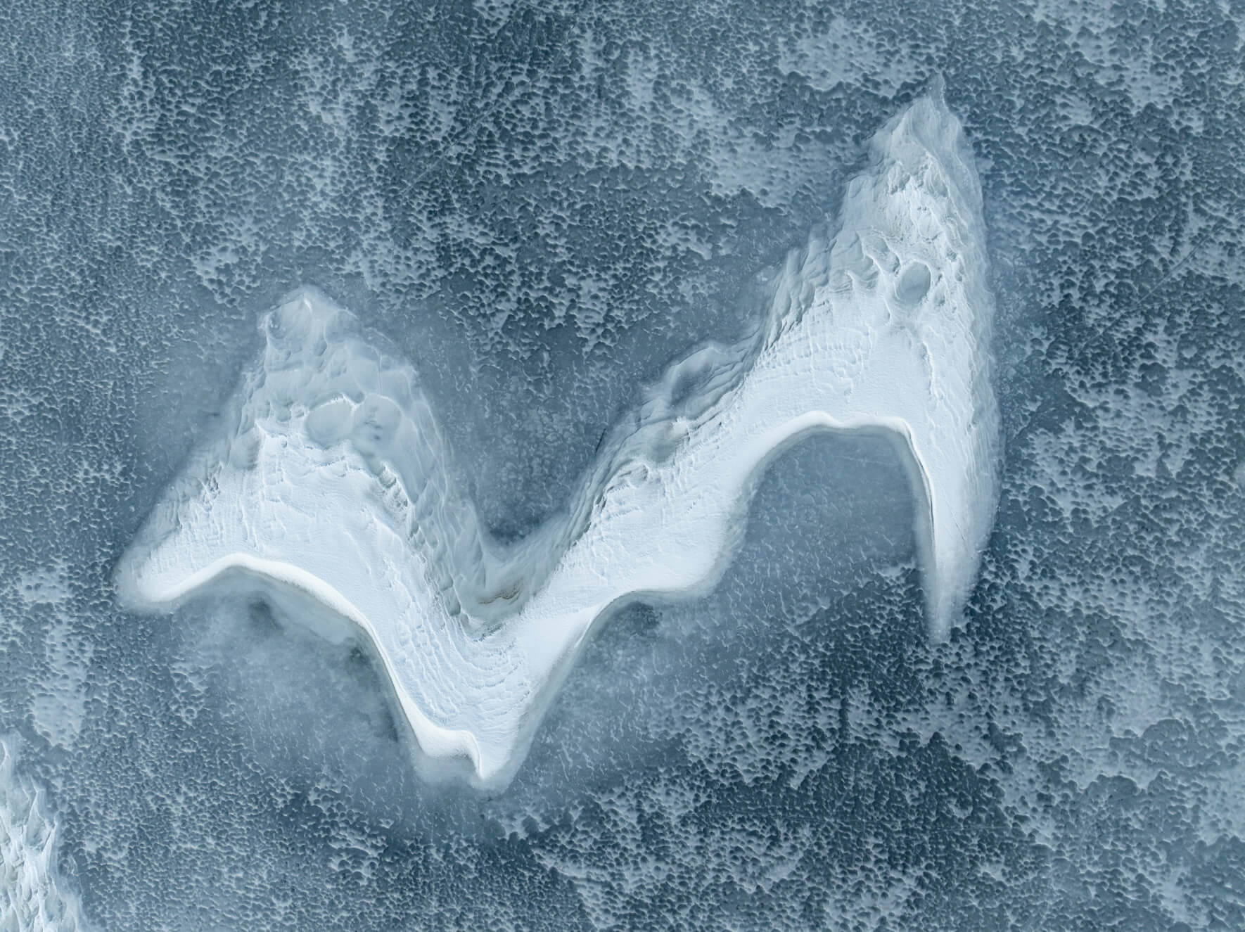 Frozen lake in Norway surface showing curved snow patterns