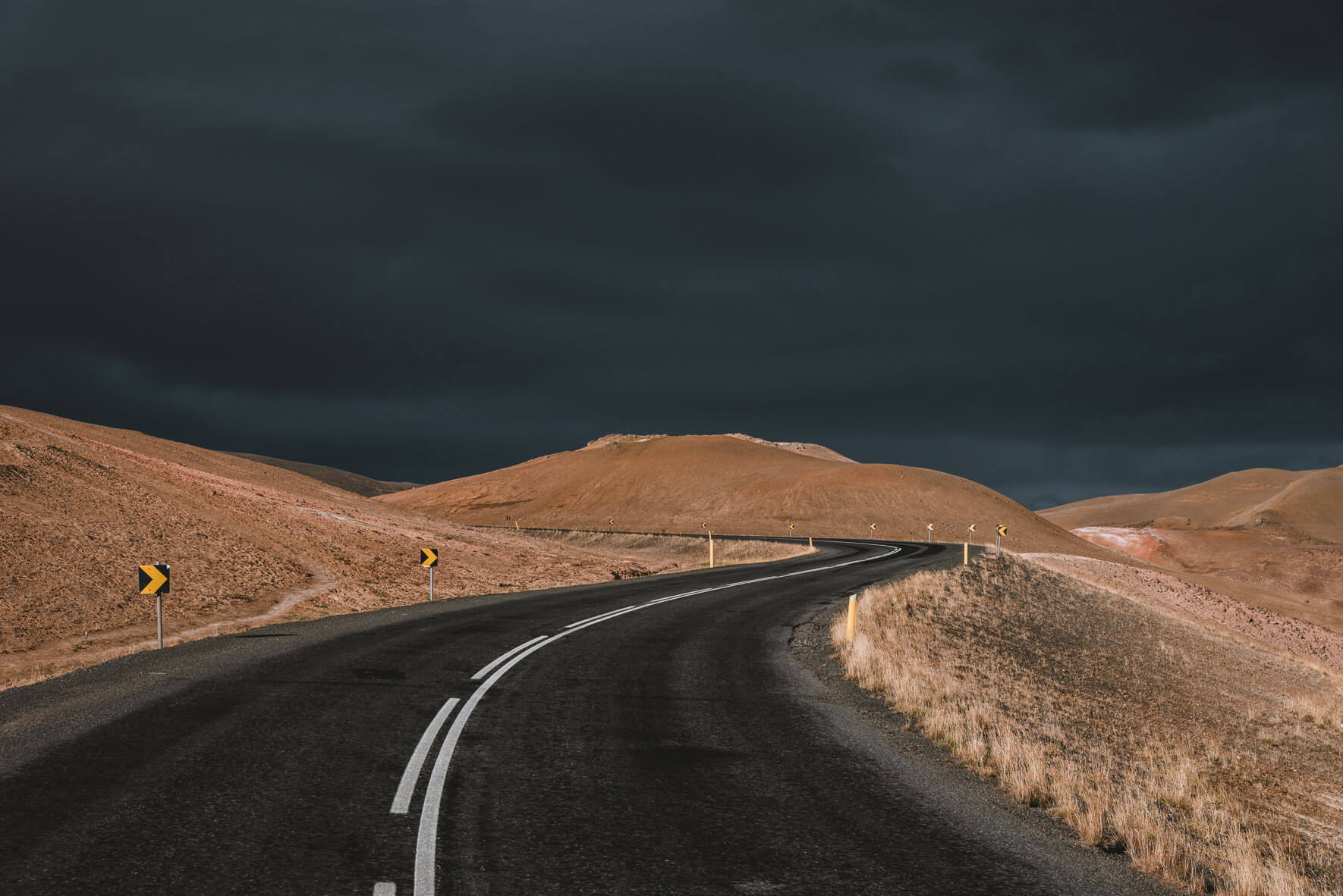 Road over Námafjall mountain in Iceland with dark storm clouds